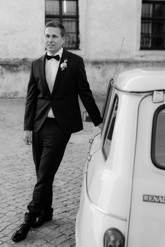 A groom standing next to the wedding car and waiting for his bride