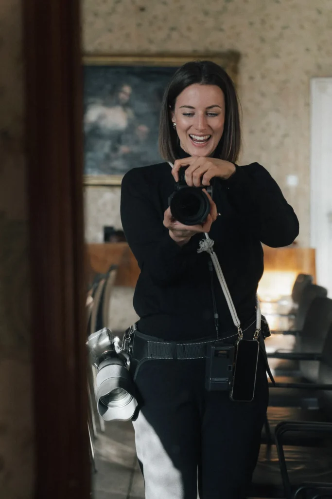 Persönliches Porträt der Fotografin Maria Bruckmaier, lachend mit Kamera in der Hand – eingefangen in einem warmen Moment voller Leichtigkeit und Freude.