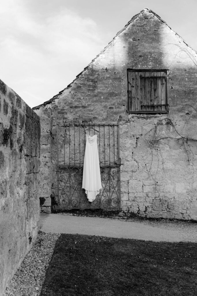 Elegant wedding dress hanging on rustic gate, evoking timeless aesthetics